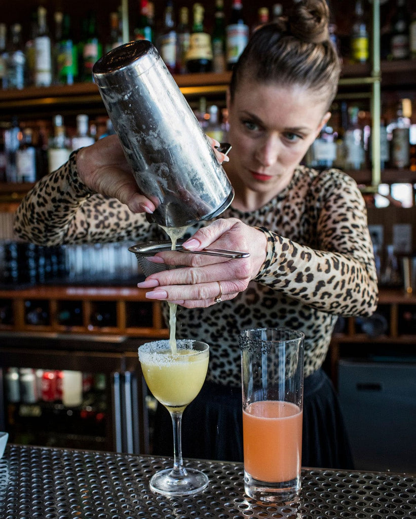 woman bartender making yellow drink