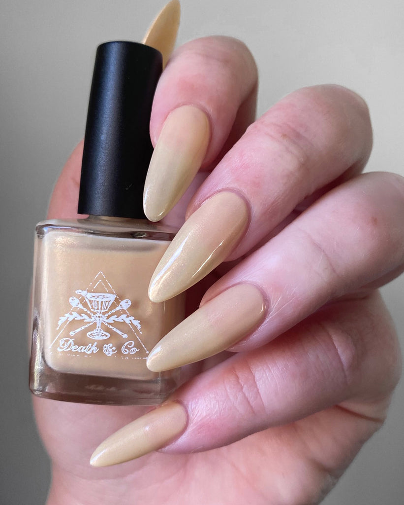 hand holding Almond with daffodil yellow undertones and a subtle pink shimmer nail polish