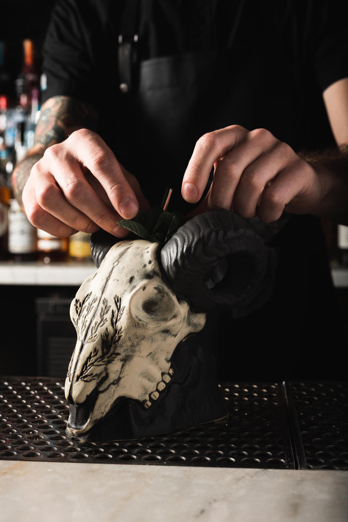 bartender putting straw in big horn sheep shaped cocktail mug