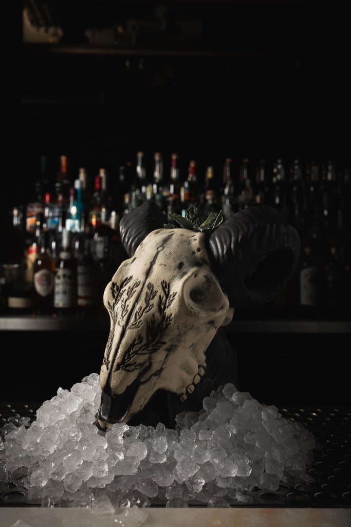 big horn sheep shaped cocktail mug on bar with ice around it