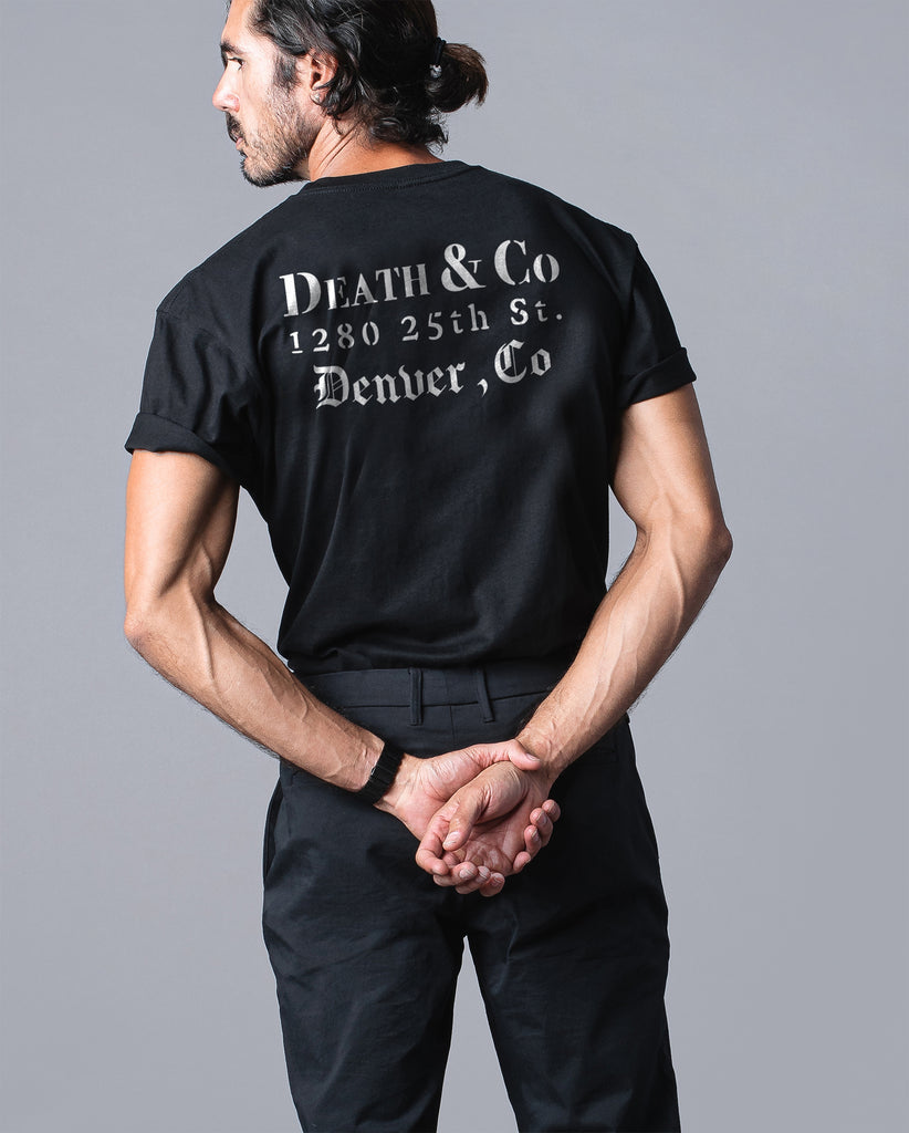 back of man wearing black tee with "death & co. 1280 25th st. denever, co."