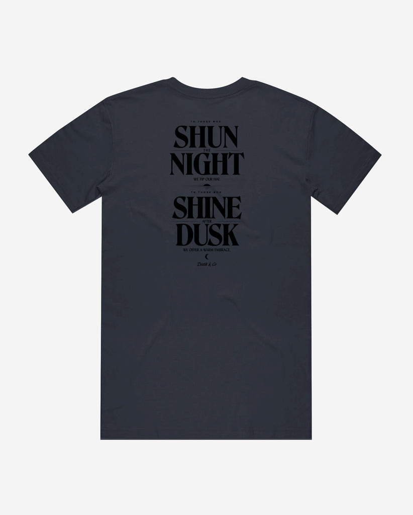 back of navy tee with "to those who shun the night we tip our hat. To those who shine after dusk we offer a warm embrace"