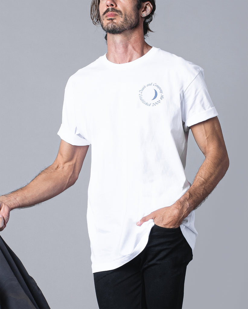 man wearing  white tee with "death and company established 2006 NYC" in circle around moon graphic on pocket