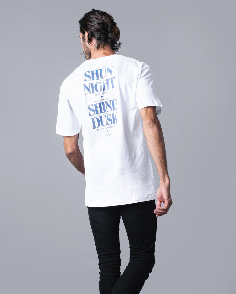 back of man wearing white tee with "to those who shun the night we tip our hat. To those who shine after dusk we offer a warm embrace"