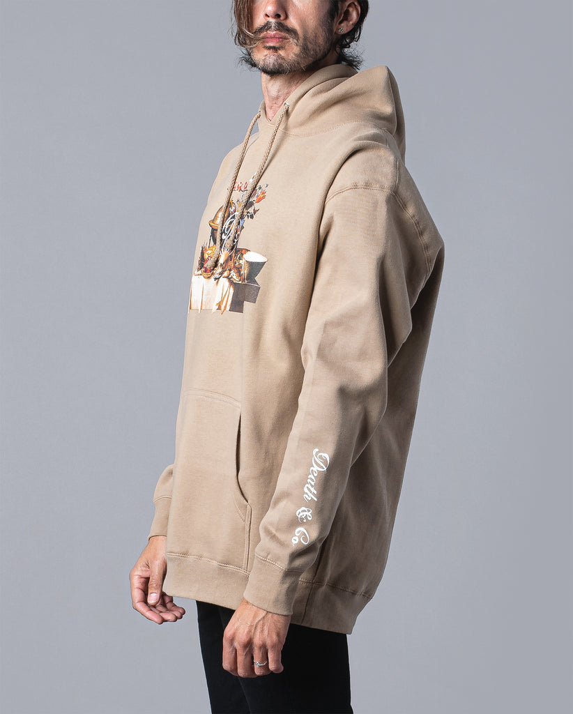 man wearing tan hoodie with table of food and drinks graphic with death & co. logo and death & co. on sleeve 