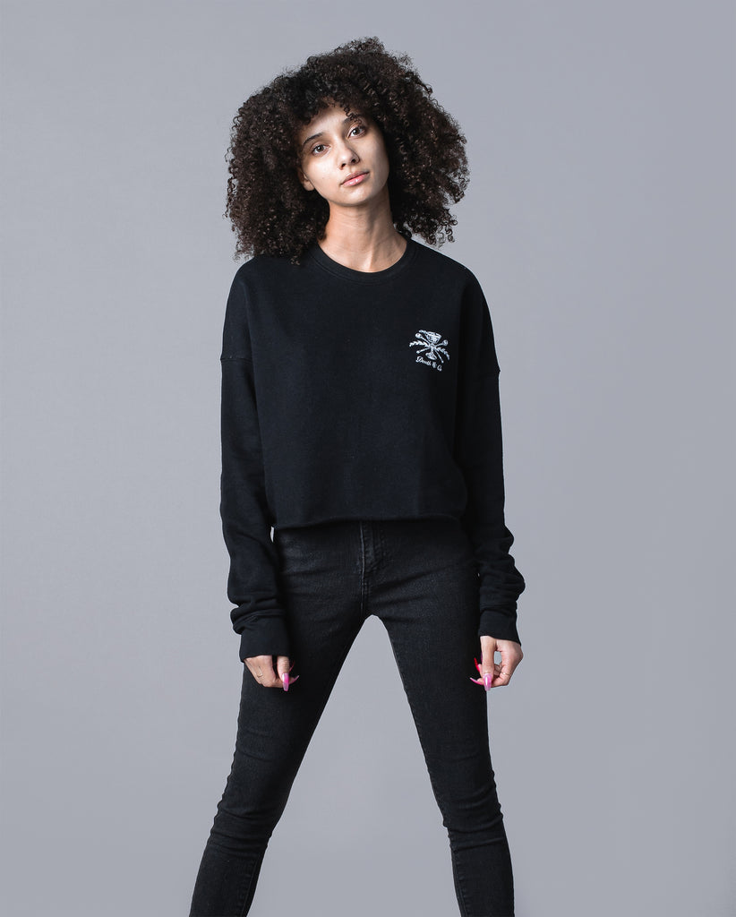 woman wearing black cropped crewneck with death & co. crest on pocket